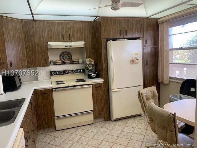 kitchen featuring dark brown cabinets, white appliances, ceiling fan, and sink