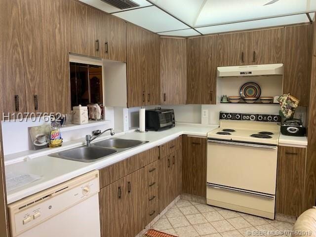 kitchen featuring sink, light tile patterned flooring, and white appliances