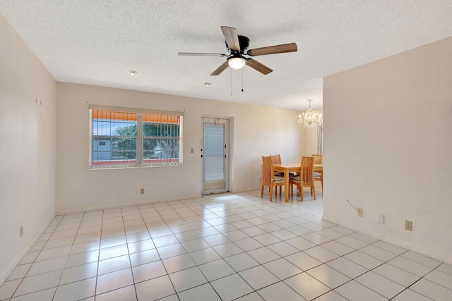 tiled empty room featuring a textured ceiling and ceiling fan with notable chandelier