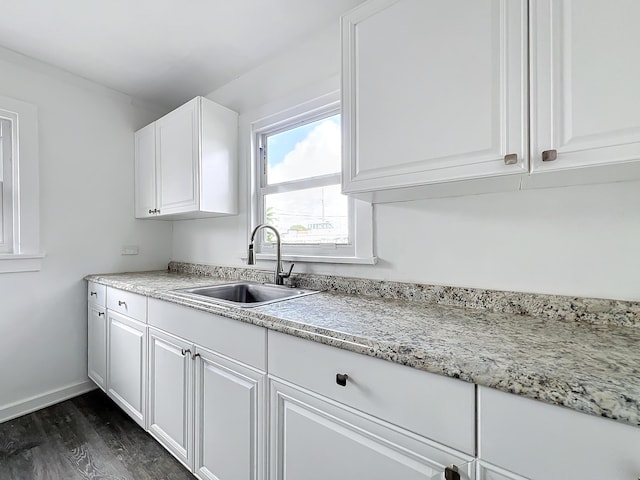 kitchen with dark hardwood / wood-style floors, light stone counters, white cabinetry, and sink