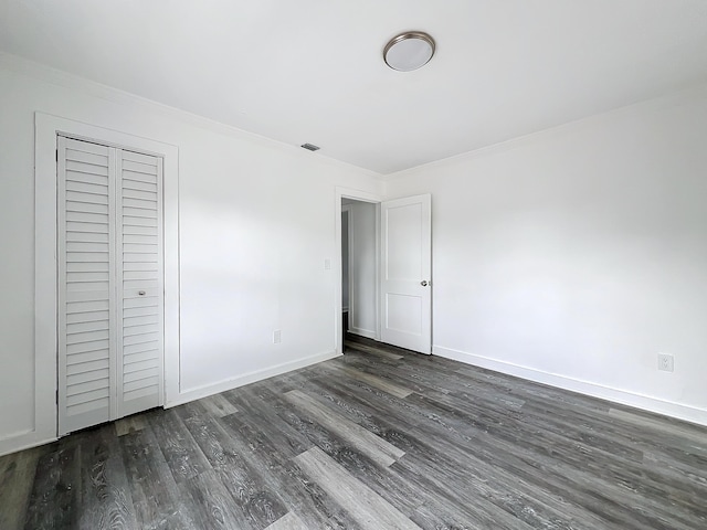 unfurnished bedroom featuring dark hardwood / wood-style flooring, a closet, and ornamental molding