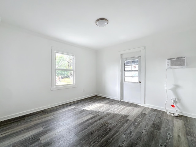 spare room featuring an AC wall unit and dark hardwood / wood-style flooring