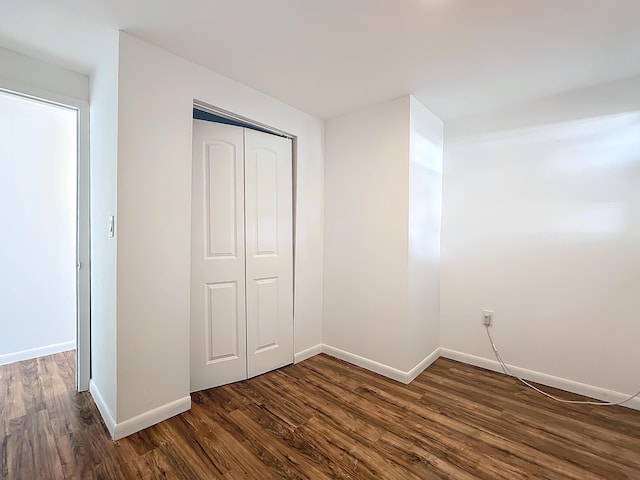 unfurnished bedroom featuring dark hardwood / wood-style flooring and a closet