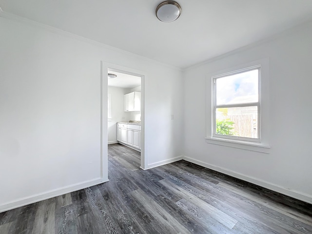 empty room with dark hardwood / wood-style floors and ornamental molding