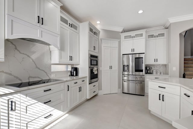 kitchen with backsplash, white cabinetry, stainless steel appliances, and ornamental molding