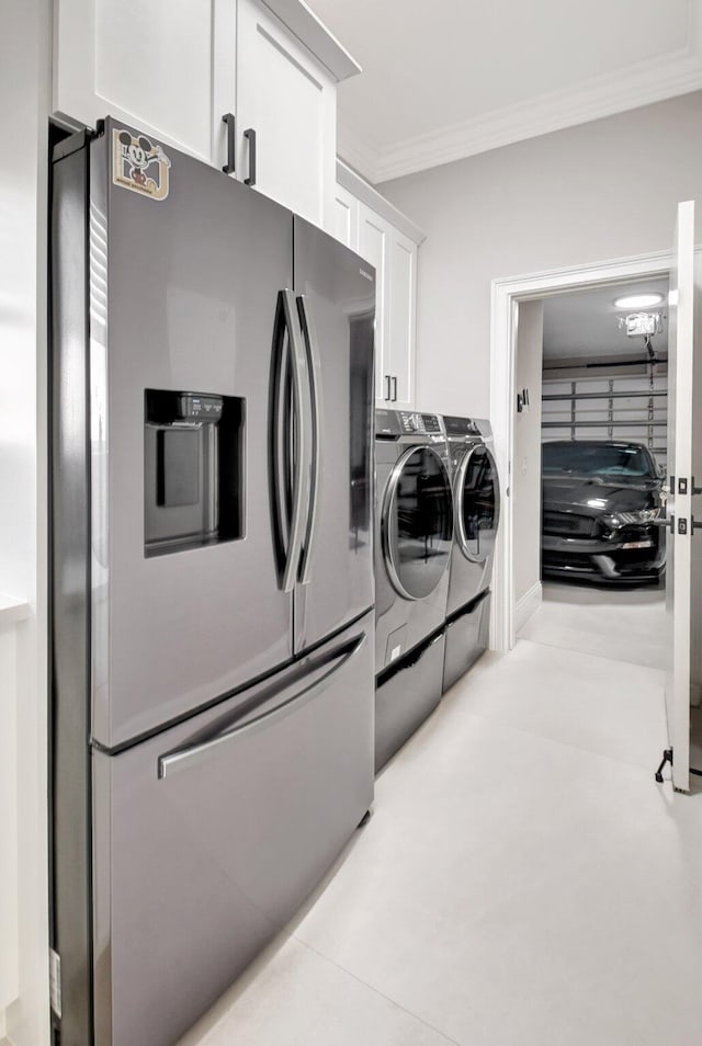 laundry room with washer and dryer, ornamental molding, and cabinets