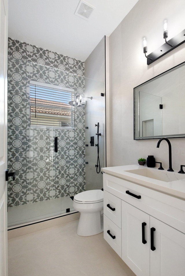 bathroom with a shower with door, vanity, and toilet