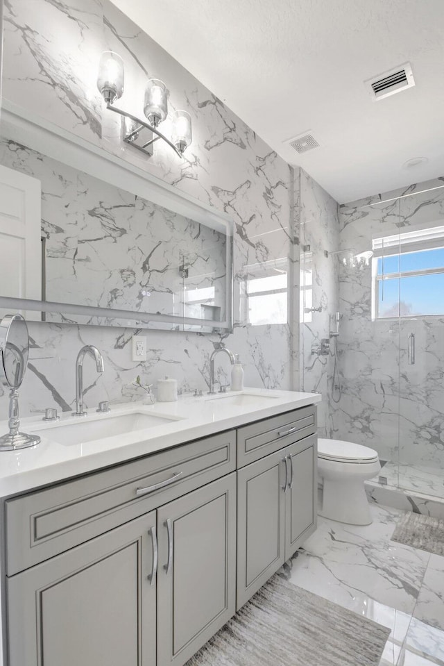 bathroom with vanity, toilet, a shower with door, and tile walls