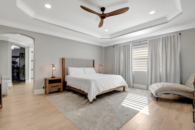 bedroom with ceiling fan, a raised ceiling, and ornamental molding