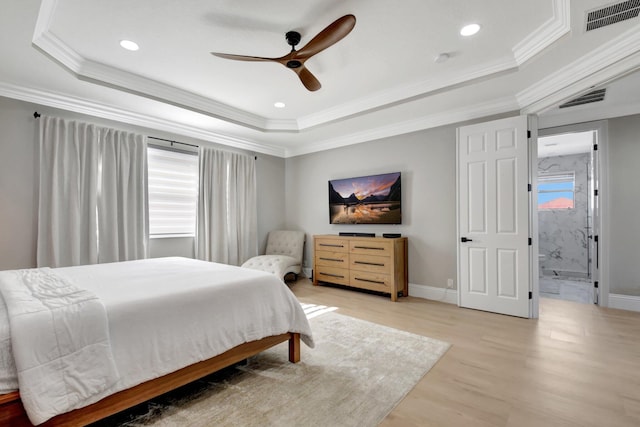 bedroom with ceiling fan, light wood-type flooring, and a tray ceiling