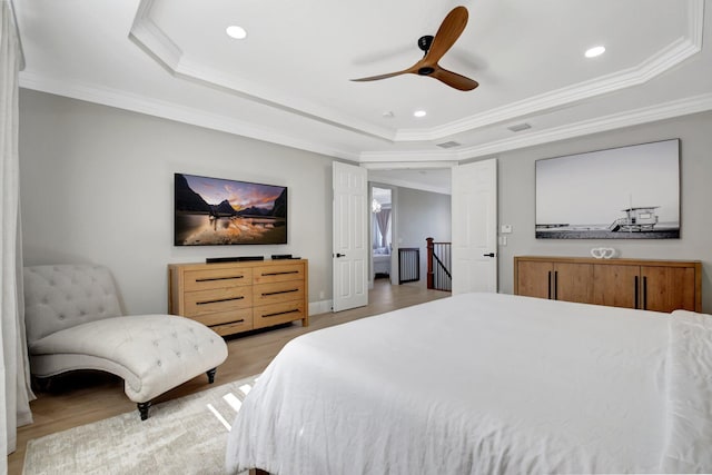 bedroom featuring a raised ceiling, ceiling fan, crown molding, and light hardwood / wood-style floors