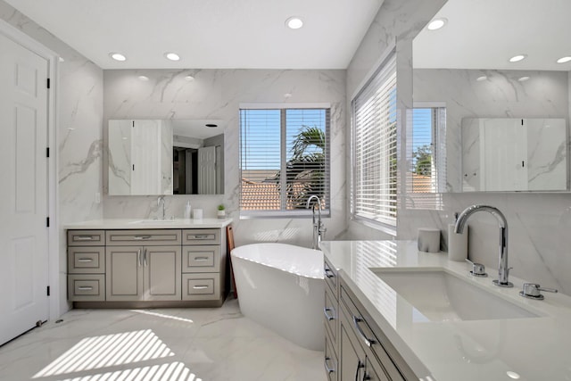 bathroom featuring plenty of natural light, a tub to relax in, vanity, and tile walls