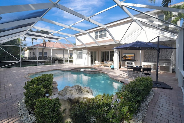 view of pool featuring an in ground hot tub, a patio, an outdoor kitchen, and glass enclosure