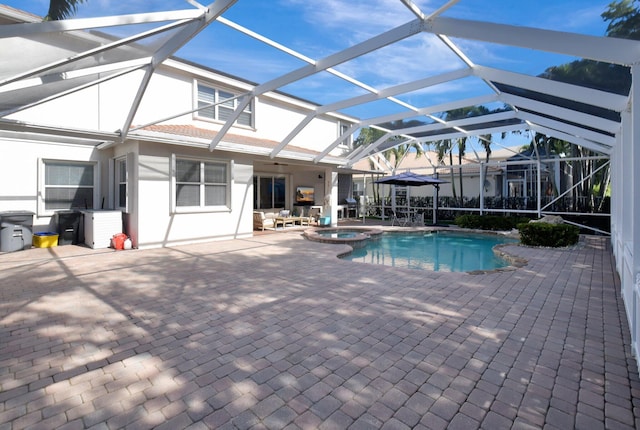 view of swimming pool with glass enclosure, an in ground hot tub, and a patio