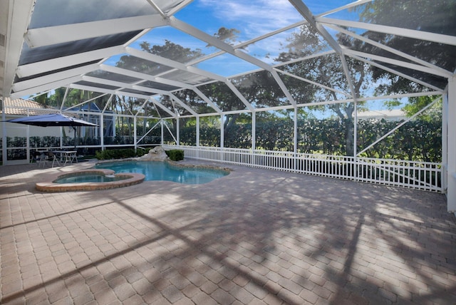 view of pool featuring glass enclosure, an in ground hot tub, and a patio