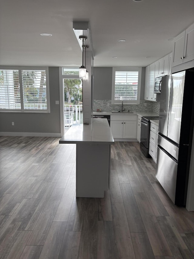 kitchen featuring a center island, stainless steel appliances, white cabinetry, and tasteful backsplash