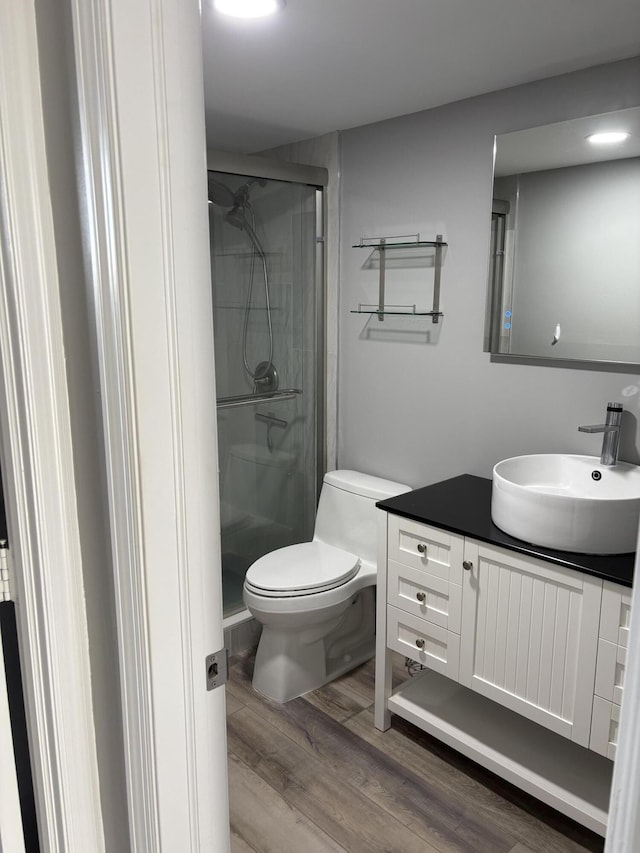 bathroom with hardwood / wood-style flooring, vanity, toilet, and a shower with shower door