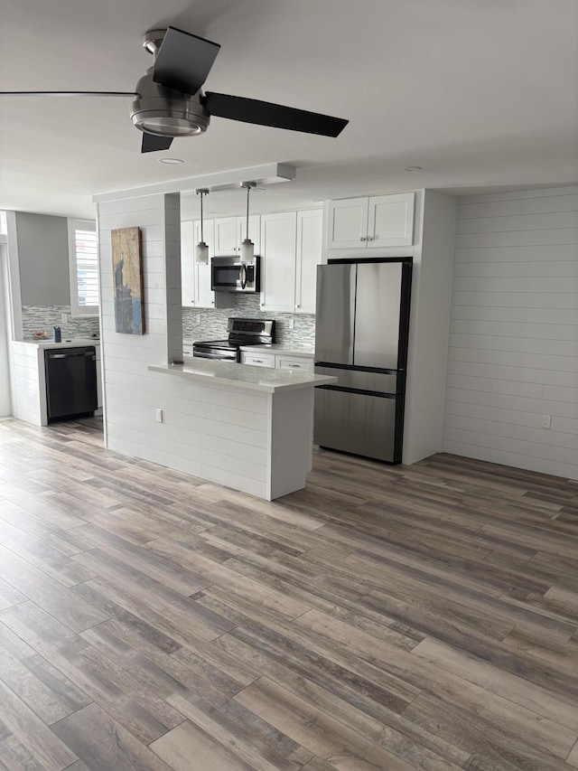 kitchen with hardwood / wood-style floors, stainless steel appliances, white cabinetry, and hanging light fixtures