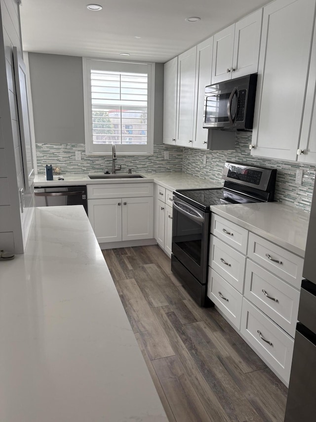 kitchen featuring dark hardwood / wood-style flooring, backsplash, stainless steel appliances, sink, and white cabinets