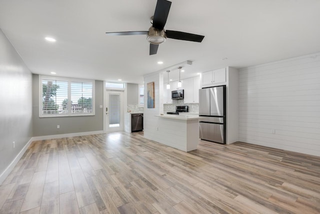 kitchen featuring appliances with stainless steel finishes, open floor plan, decorative light fixtures, light countertops, and white cabinetry