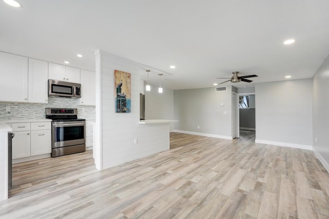 kitchen with stainless steel appliances, white cabinets, light countertops, and open floor plan