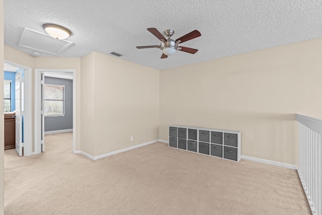 spare room with a textured ceiling, ceiling fan, and light carpet