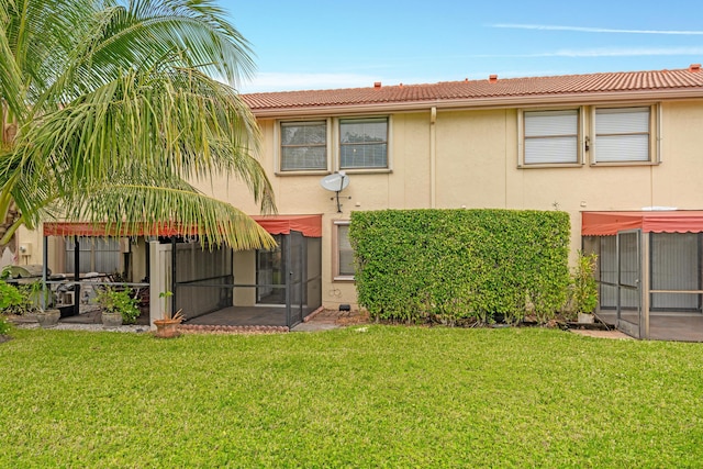 back of property with a lawn and a sunroom