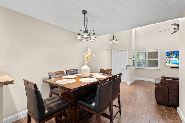 dining space featuring a textured ceiling, ceiling fan with notable chandelier, and hardwood / wood-style flooring