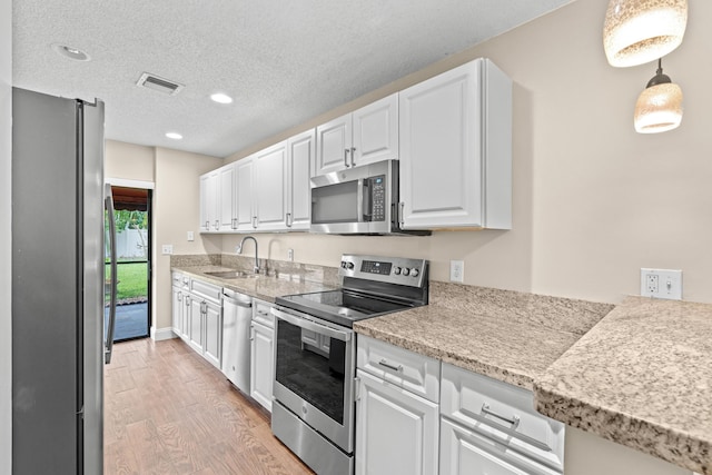 kitchen featuring white cabinetry, sink, pendant lighting, a textured ceiling, and appliances with stainless steel finishes