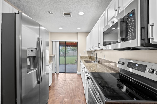 kitchen with light stone countertops, white cabinetry, sink, and stainless steel appliances