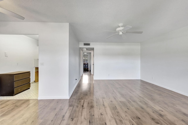 spare room featuring ceiling fan, light wood-type flooring, and a textured ceiling