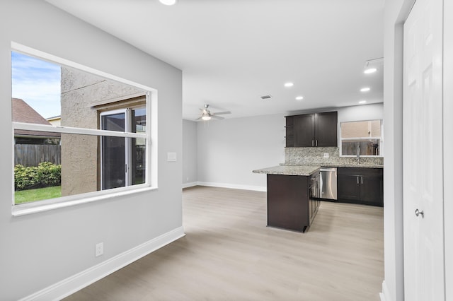 kitchen with dark brown cabinetry, a center island, tasteful backsplash, stainless steel dishwasher, and plenty of natural light