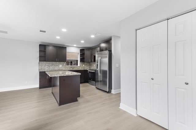 kitchen with backsplash, light hardwood / wood-style flooring, a kitchen island, dark brown cabinetry, and stainless steel appliances