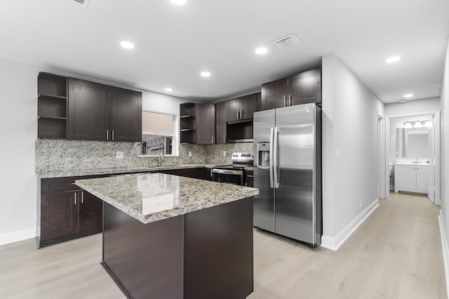 kitchen with a center island, light wood-type flooring, appliances with stainless steel finishes, tasteful backsplash, and dark brown cabinetry