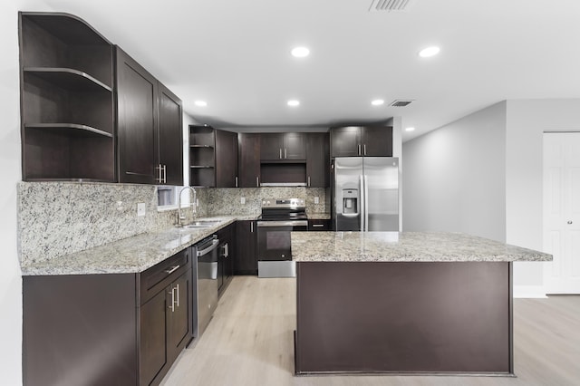 kitchen with sink, a center island, stainless steel appliances, light hardwood / wood-style floors, and dark brown cabinets