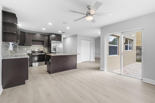 kitchen with sink, a center island, dark brown cabinets, appliances with stainless steel finishes, and light wood-type flooring