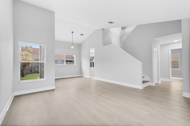 unfurnished living room with lofted ceiling and light wood-type flooring