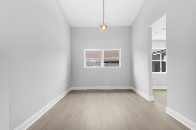 spare room featuring light hardwood / wood-style floors and a notable chandelier