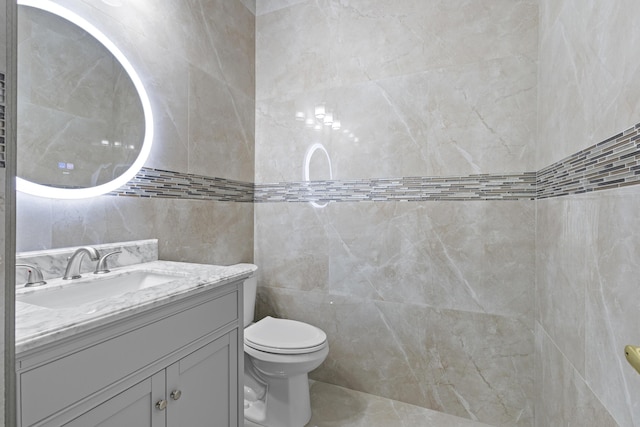 bathroom featuring vanity, toilet, and tile walls