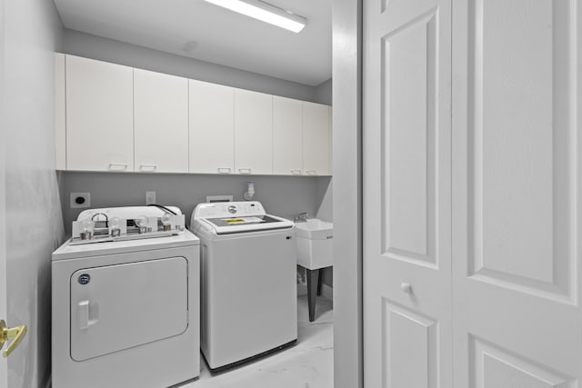 clothes washing area featuring washing machine and clothes dryer and cabinets