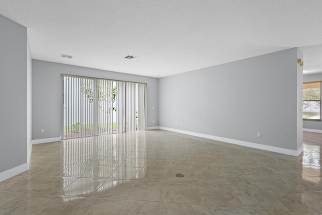 tiled empty room featuring a textured ceiling