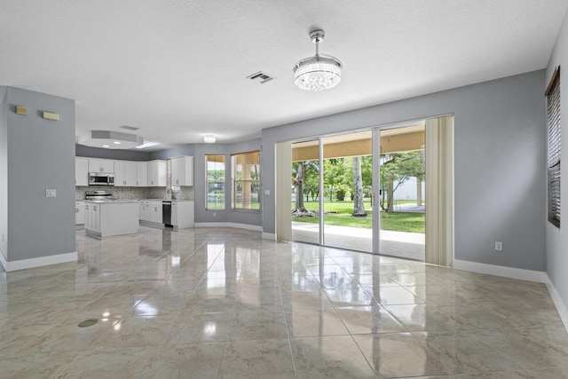 unfurnished living room featuring a textured ceiling and a notable chandelier