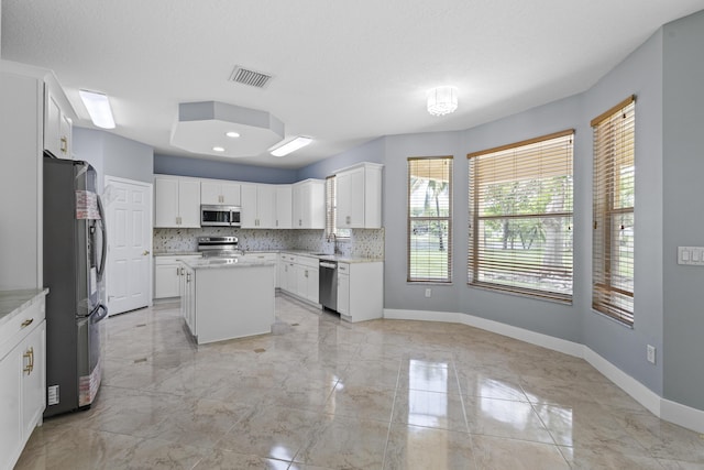 kitchen featuring backsplash, a center island, white cabinets, and stainless steel appliances