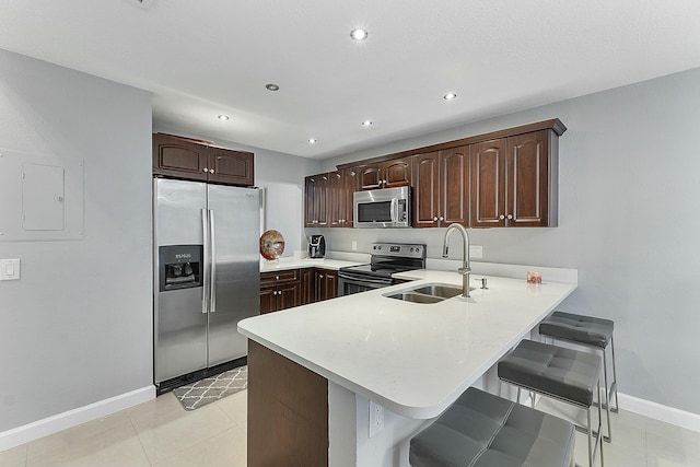 kitchen with a breakfast bar, sink, appliances with stainless steel finishes, dark brown cabinets, and kitchen peninsula