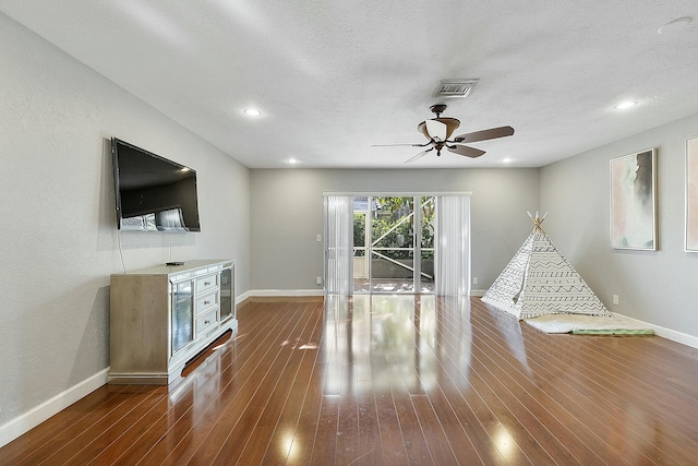 unfurnished living room with ceiling fan, a textured ceiling, and dark wood-type flooring