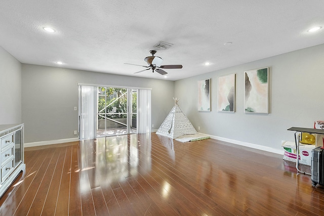 unfurnished living room featuring ceiling fan, dark hardwood / wood-style floors, and a textured ceiling