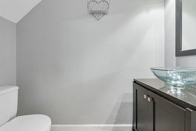 bathroom with vanity, lofted ceiling, and toilet