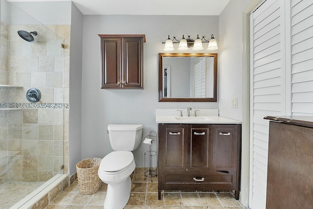 bathroom featuring vanity, toilet, and a tile shower