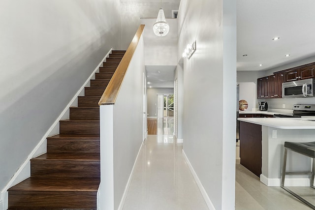 staircase with tile patterned floors and a notable chandelier