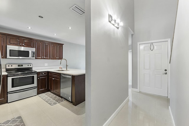 kitchen featuring appliances with stainless steel finishes, dark brown cabinetry, light tile patterned floors, and sink